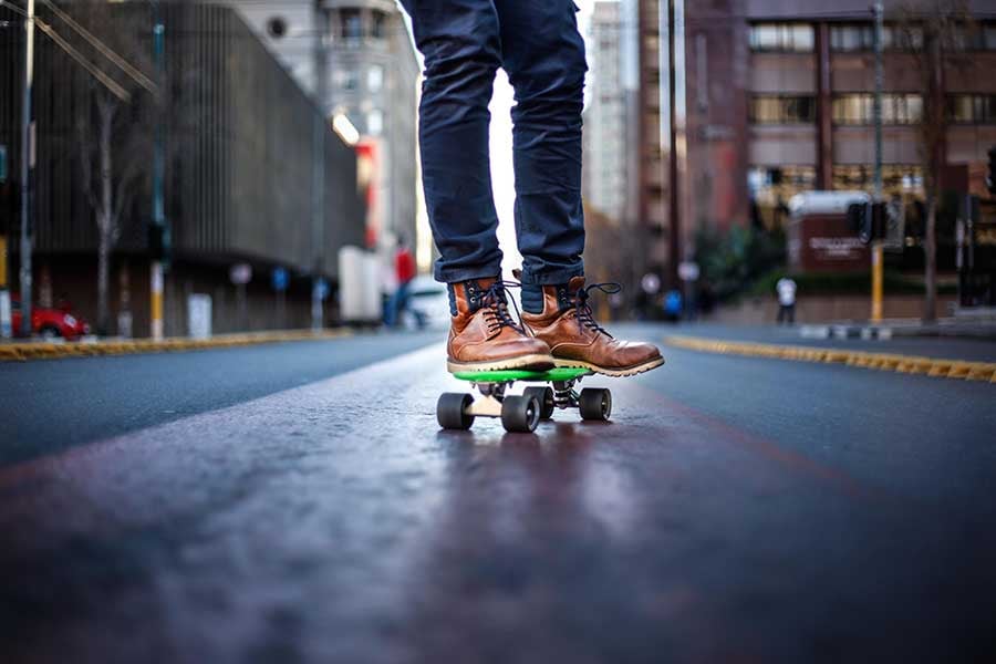 Skateboarder on a dark street from the feet down.